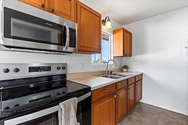 kitchen with appliances with stainless steel finishes, dark tile patterned flooring, sink, and electric panel