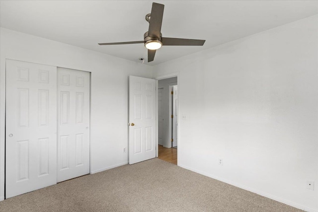 unfurnished bedroom with ceiling fan, a closet, and light carpet