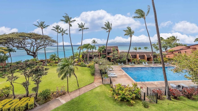 view of swimming pool featuring a yard and a water view