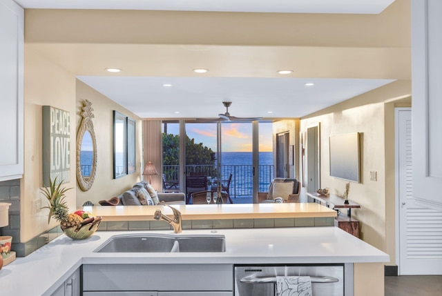 kitchen with a sink, stainless steel dishwasher, recessed lighting, a peninsula, and light countertops