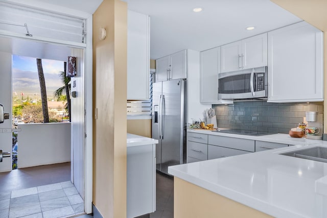 kitchen with decorative backsplash, white cabinetry, appliances with stainless steel finishes, and light countertops