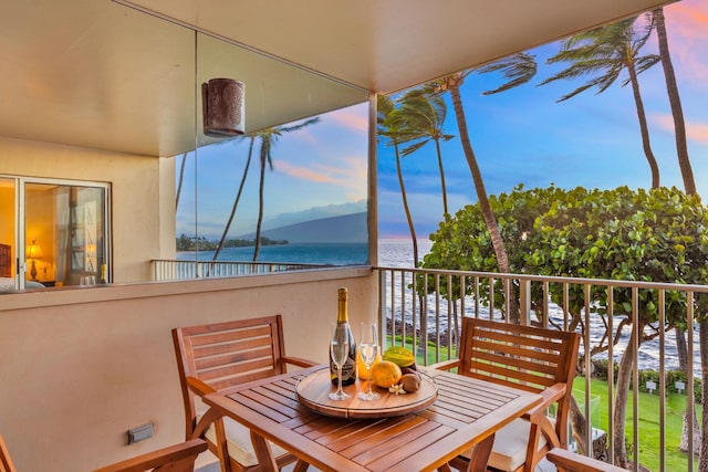 balcony with a water view and outdoor dining space