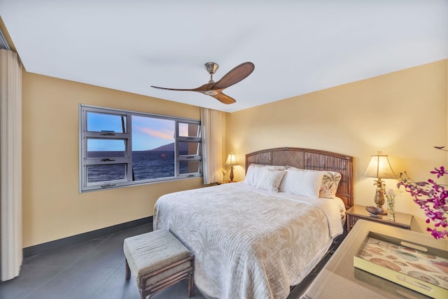 tiled bedroom with ceiling fan and baseboards