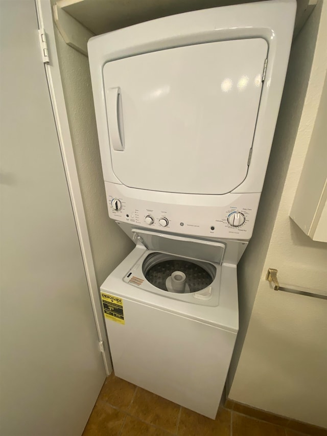 laundry area with stacked washer and dryer and dark tile patterned flooring