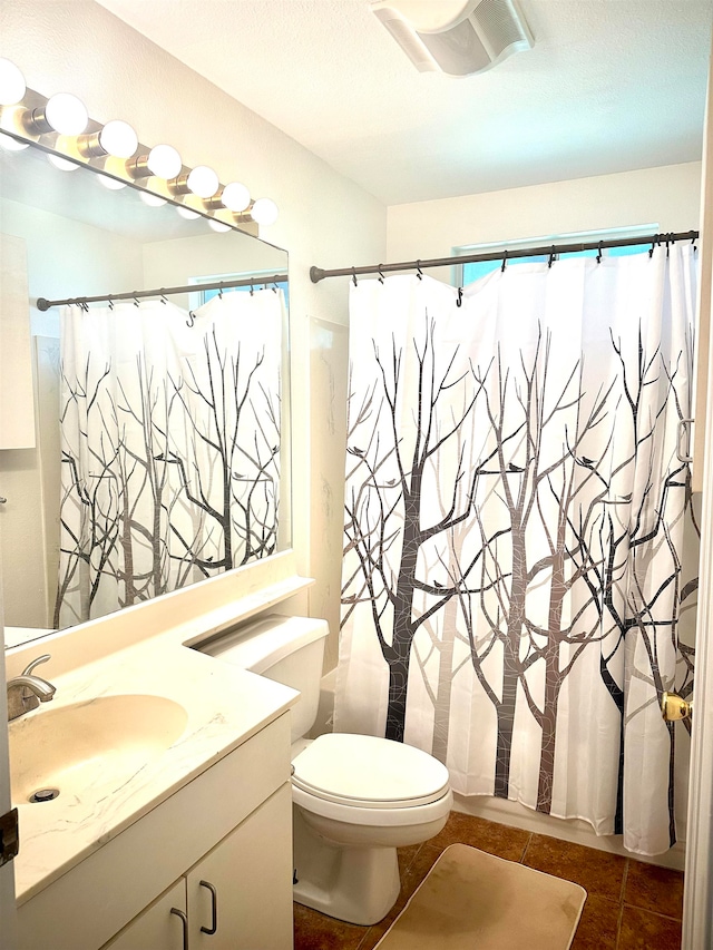 bathroom featuring walk in shower, vanity, toilet, and tile patterned floors