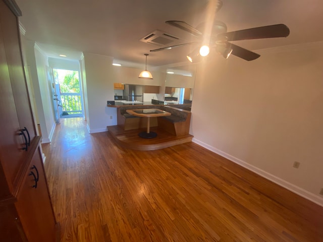 kitchen with pendant lighting, hardwood / wood-style flooring, stainless steel refrigerator, ornamental molding, and ceiling fan