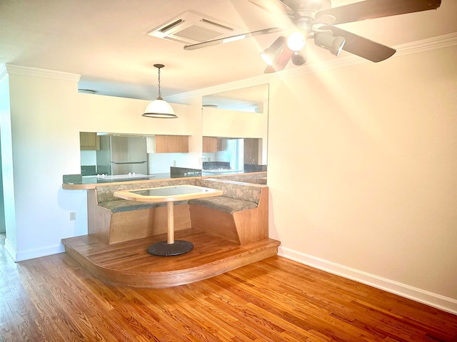 kitchen featuring kitchen peninsula, hardwood / wood-style floors, ornamental molding, ceiling fan, and stainless steel fridge