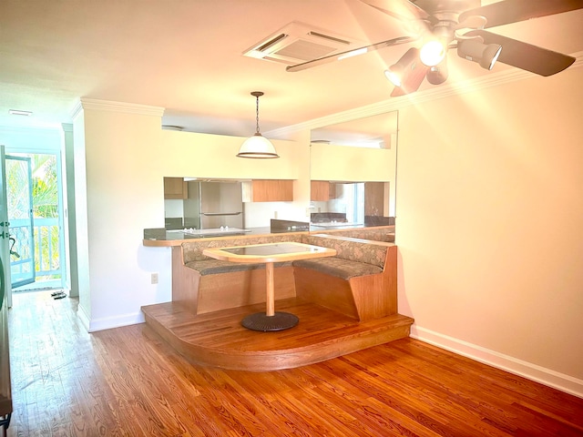 kitchen featuring ceiling fan, stainless steel fridge, kitchen peninsula, hardwood / wood-style flooring, and crown molding