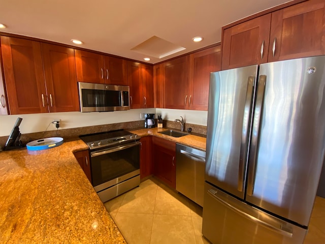 kitchen with light tile patterned floors, appliances with stainless steel finishes, light stone counters, and sink