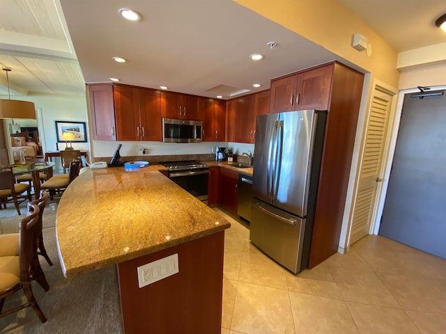 kitchen featuring light tile patterned flooring, light stone counters, stainless steel appliances, and sink