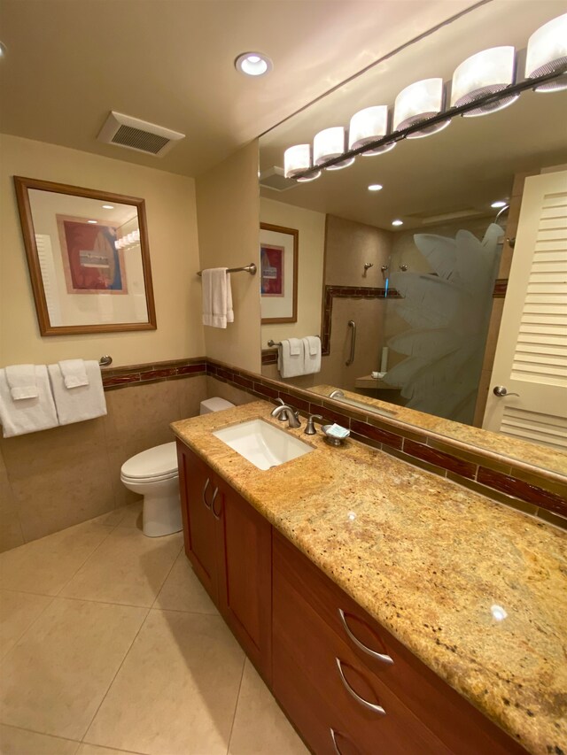 bathroom featuring vanity, walk in shower, tile patterned flooring, tile walls, and toilet