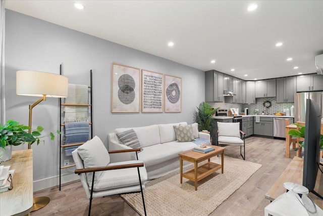 living room with a wall mounted AC and light hardwood / wood-style floors