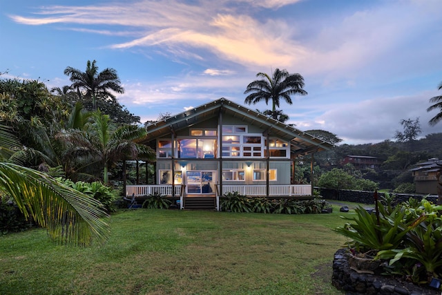 back house at dusk with a yard and a wooden deck