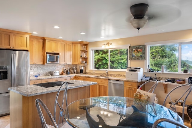 kitchen featuring ceiling fan, sink, tasteful backsplash, light stone counters, and appliances with stainless steel finishes