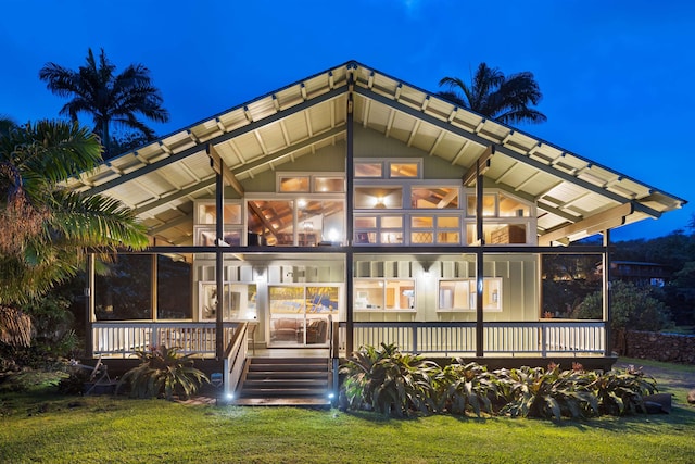 back house at night with a sunroom and a yard