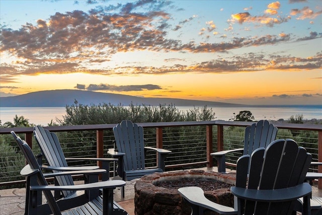 deck at dusk featuring a water view and an outdoor fire pit