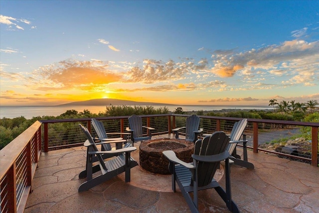 patio terrace at dusk featuring a water and mountain view and a fire pit