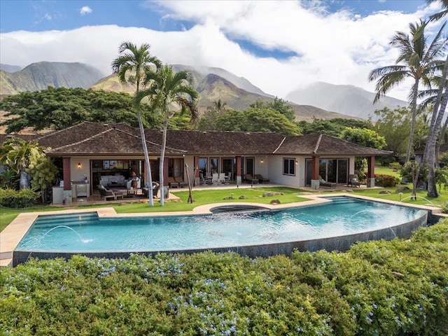 view of swimming pool with pool water feature, a mountain view, and a patio