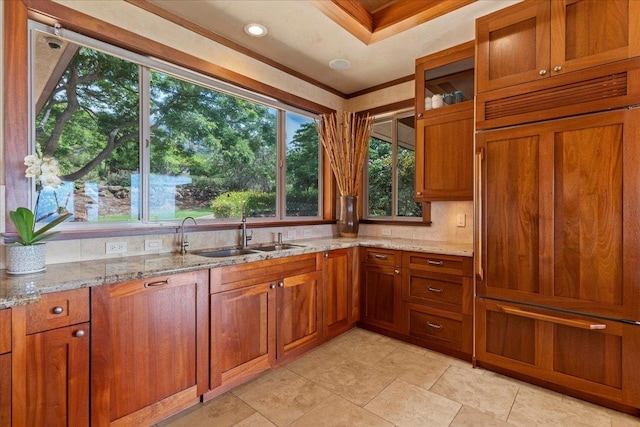 kitchen featuring ornamental molding, sink, light stone counters, and backsplash