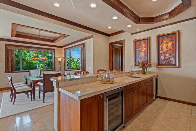 kitchen with wine cooler, light stone counters, sink, and kitchen peninsula