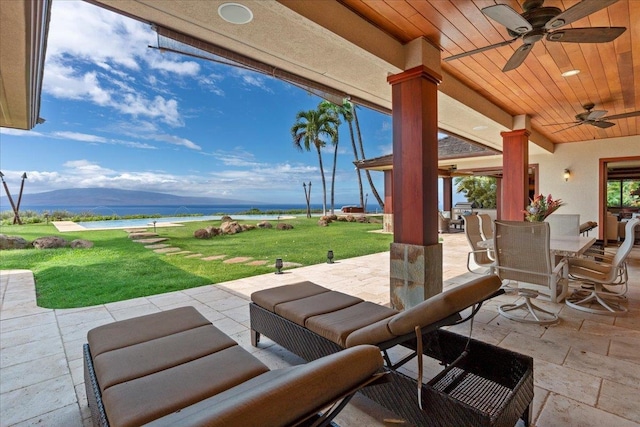 view of patio / terrace featuring a water and mountain view, outdoor lounge area, and ceiling fan