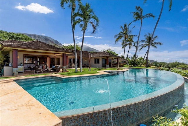 view of swimming pool with a hot tub, a patio area, a mountain view, and outdoor lounge area