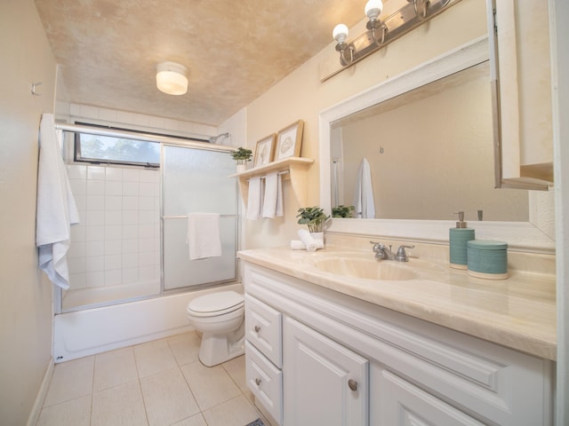 full bathroom featuring vanity, tile patterned flooring, combined bath / shower with glass door, and toilet