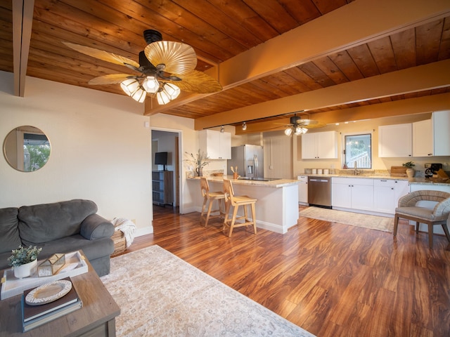 living room with ceiling fan, beamed ceiling, and dark wood-type flooring