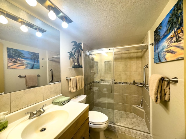 bathroom with tile patterned flooring, toilet, a shower with shower door, vanity, and a textured ceiling