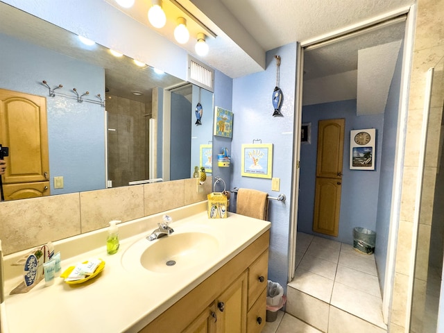 bathroom with a tile shower, tile patterned floors, vanity, and a textured ceiling