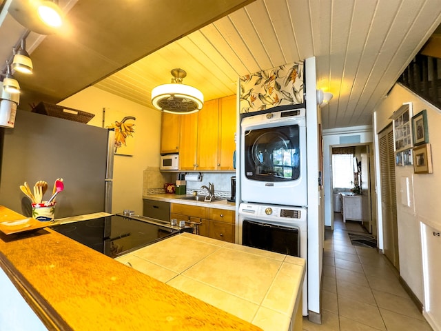 kitchen featuring stacked washer and dryer, decorative backsplash, white appliances, and wooden ceiling