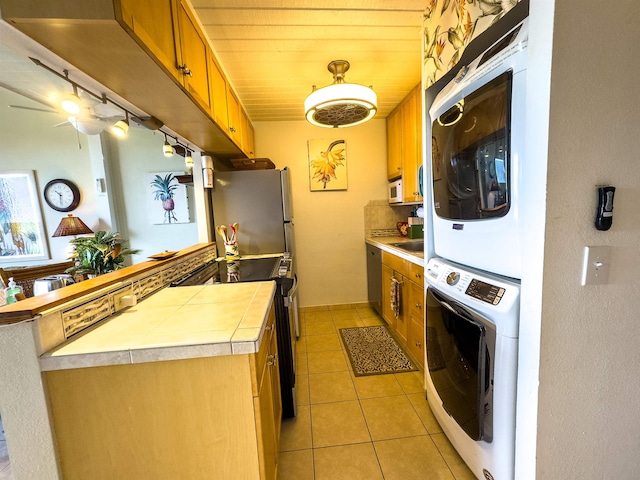 kitchen with stainless steel refrigerator, wooden ceiling, stacked washer and dryer, black electric range, and light tile patterned floors