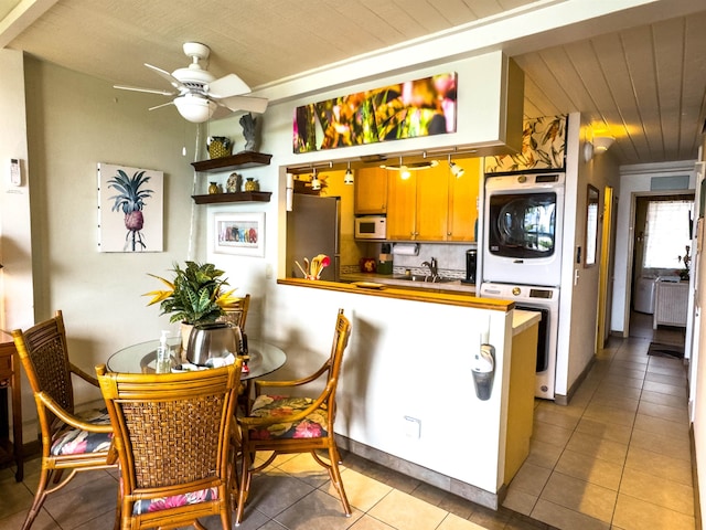 kitchen featuring stacked washing maching and dryer, ceiling fan, white appliances, wooden ceiling, and tile patterned floors