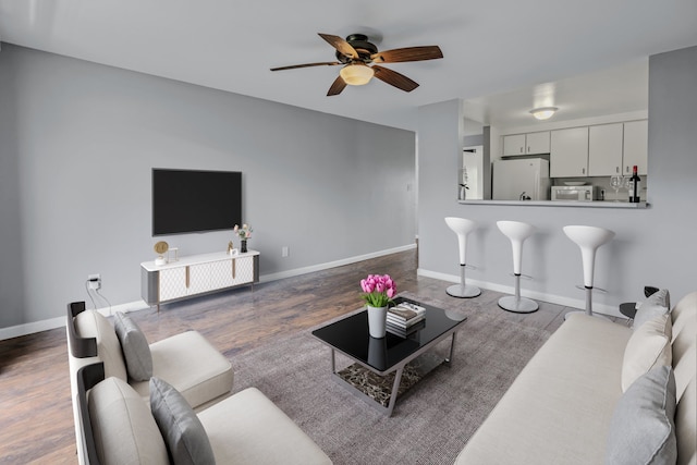 living room with ceiling fan and dark hardwood / wood-style floors