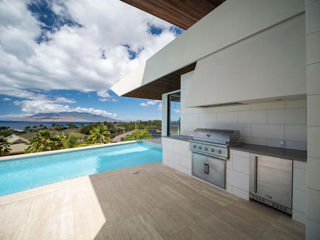 view of swimming pool with a patio area, a mountain view, a grill, and exterior kitchen