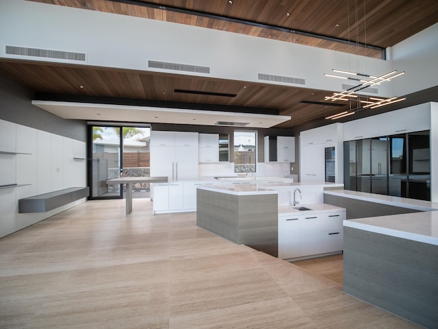 kitchen featuring wooden ceiling, white cabinets, a high ceiling, and light hardwood / wood-style flooring