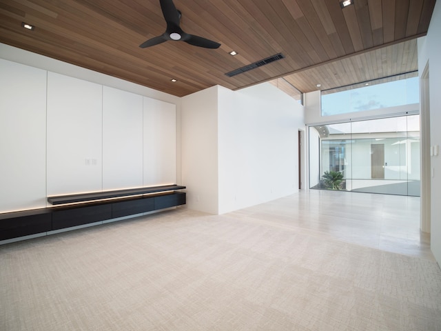 carpeted empty room with ceiling fan, expansive windows, and wooden ceiling