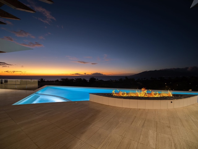 pool at dusk featuring a patio