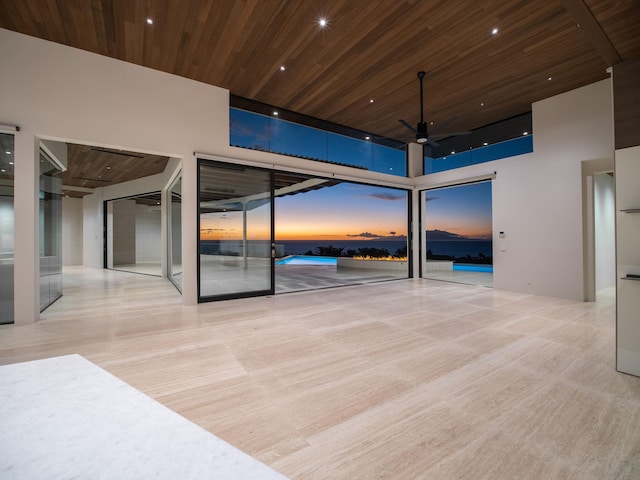 interior space with light hardwood / wood-style flooring, wooden ceiling, a high ceiling, floor to ceiling windows, and ceiling fan