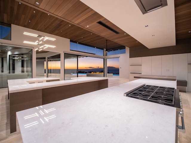 kitchen featuring floor to ceiling windows, wooden ceiling, a center island, light wood-type flooring, and white cabinets