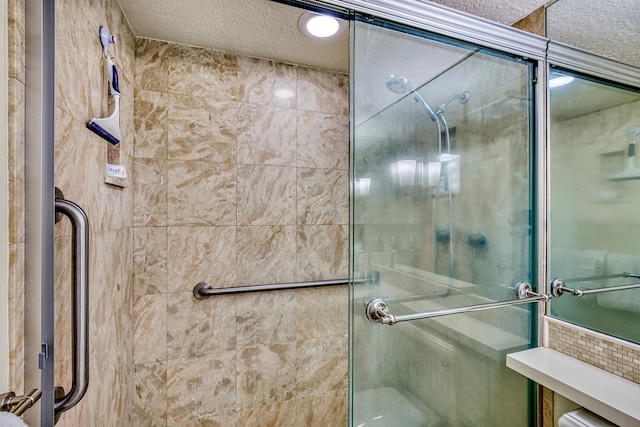 bathroom featuring a textured ceiling and a shower with door