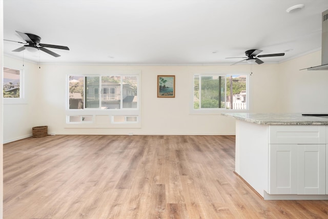 unfurnished living room featuring baseboards, light wood-style floors, ornamental molding, and a ceiling fan