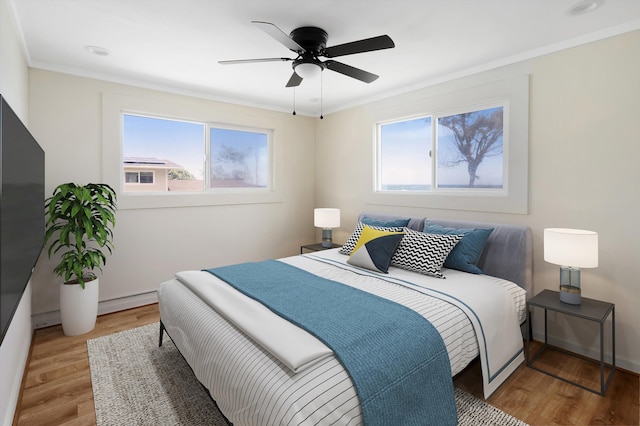 bedroom featuring multiple windows, light wood-type flooring, and crown molding