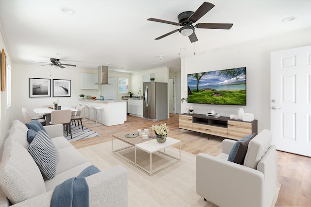 living room with a ceiling fan, crown molding, and light wood-style floors