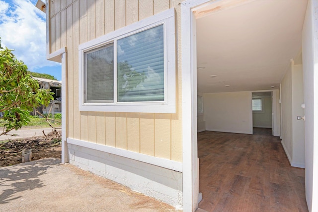 view of exterior entry featuring board and batten siding and a patio area
