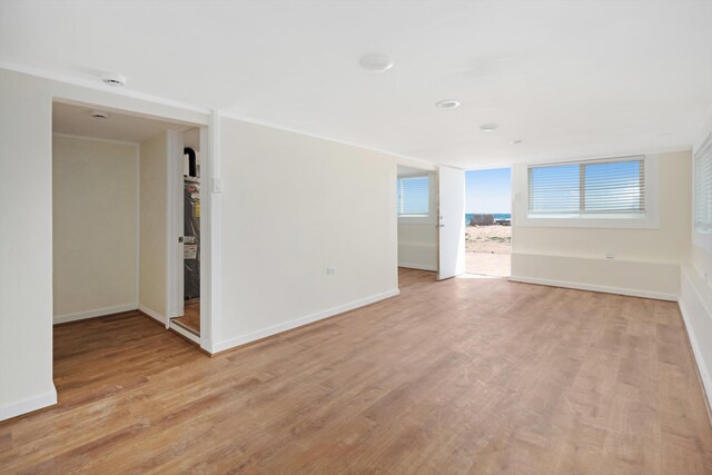 spare room with baseboards, light wood-style floors, and crown molding