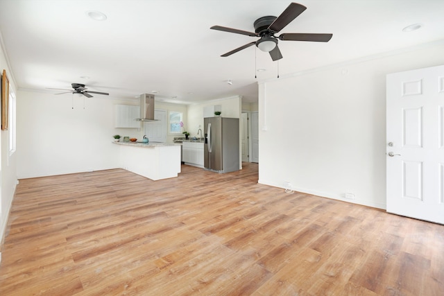 unfurnished living room featuring a ceiling fan, ornamental molding, and light wood-type flooring