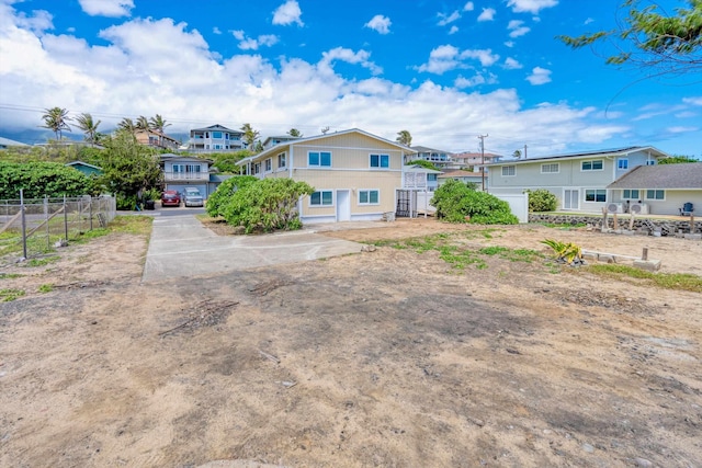 rear view of property featuring fence and concrete driveway