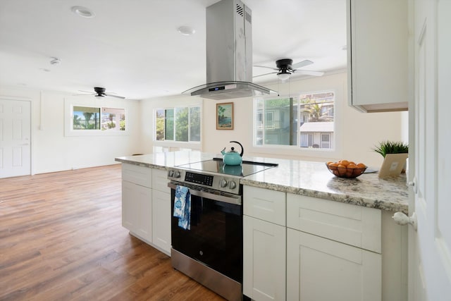 kitchen featuring stainless steel range with electric stovetop, a wealth of natural light, island exhaust hood, and ceiling fan