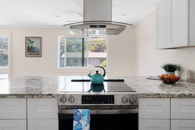 kitchen with white cabinets, island exhaust hood, crown molding, stainless steel range with electric cooktop, and light stone counters